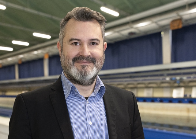 Sven Grundmann steht vor dem Schleppkanal in der Strömungshalle.