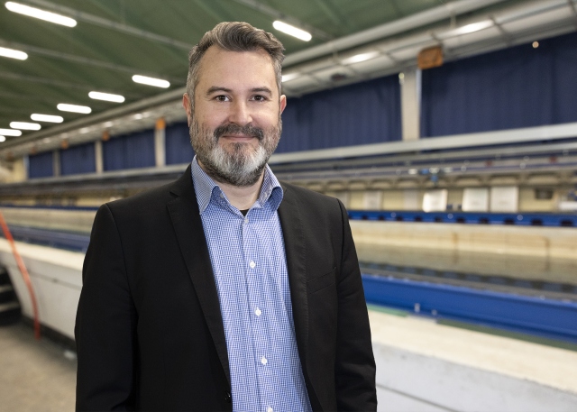 Sven Grundmann steht vor dem Schleppkanal in der Strömungshalle.